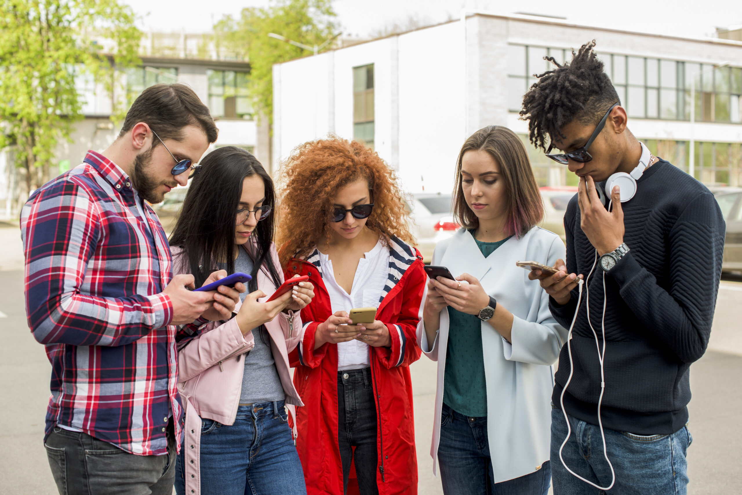 grupo-de-amigos-modernos-usando-o-celular-no-exterior